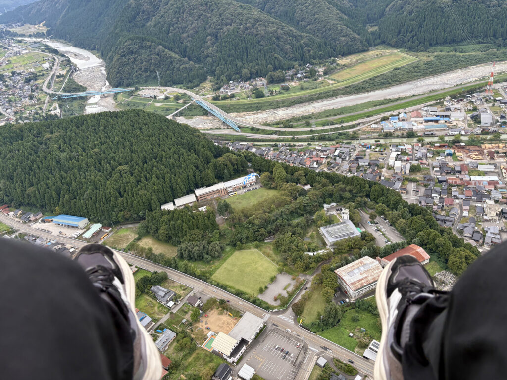 パラグライダーの眼下に広がる山と街の景色